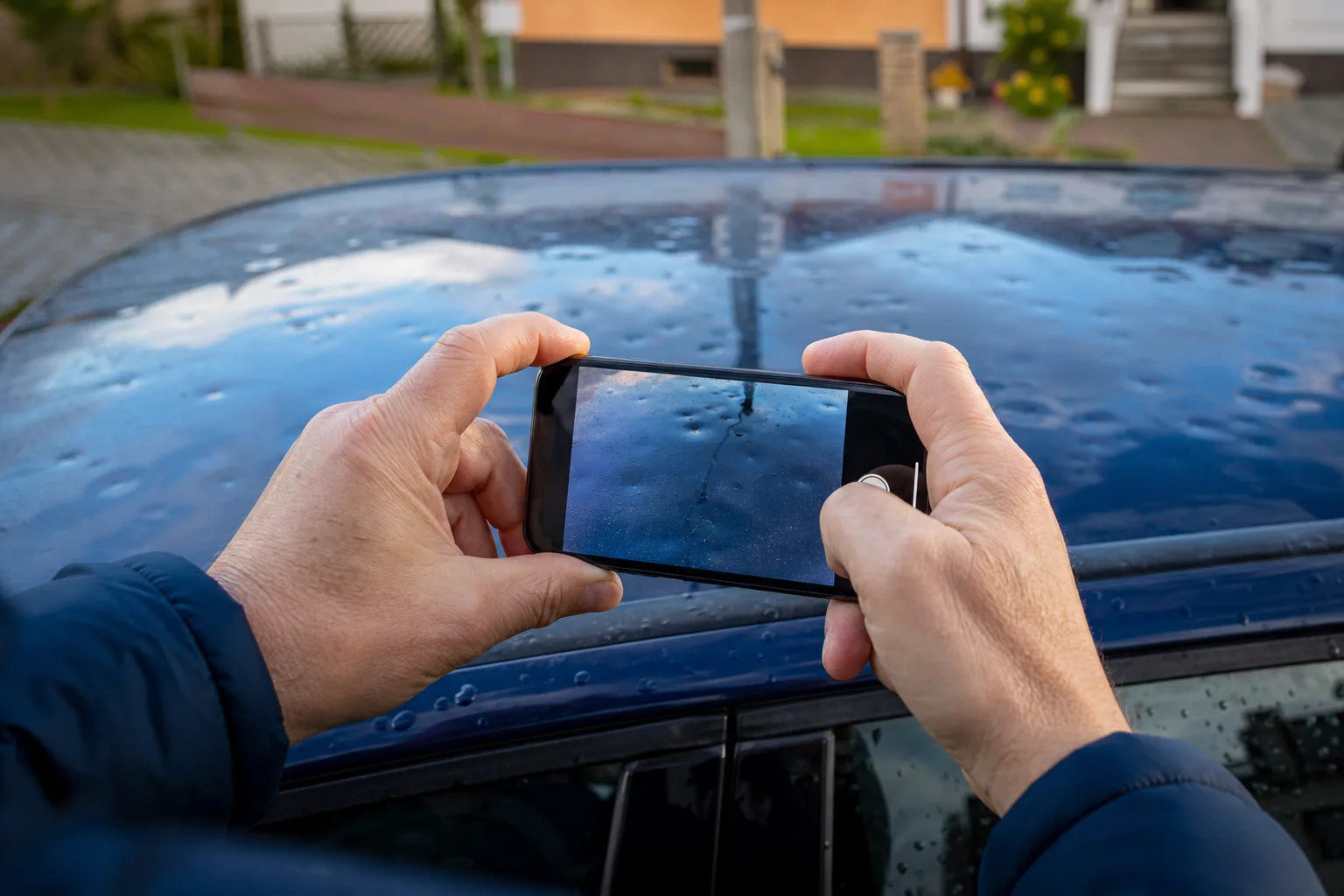 Eine Person fotografiert Hageldellen mit einem Smartphone